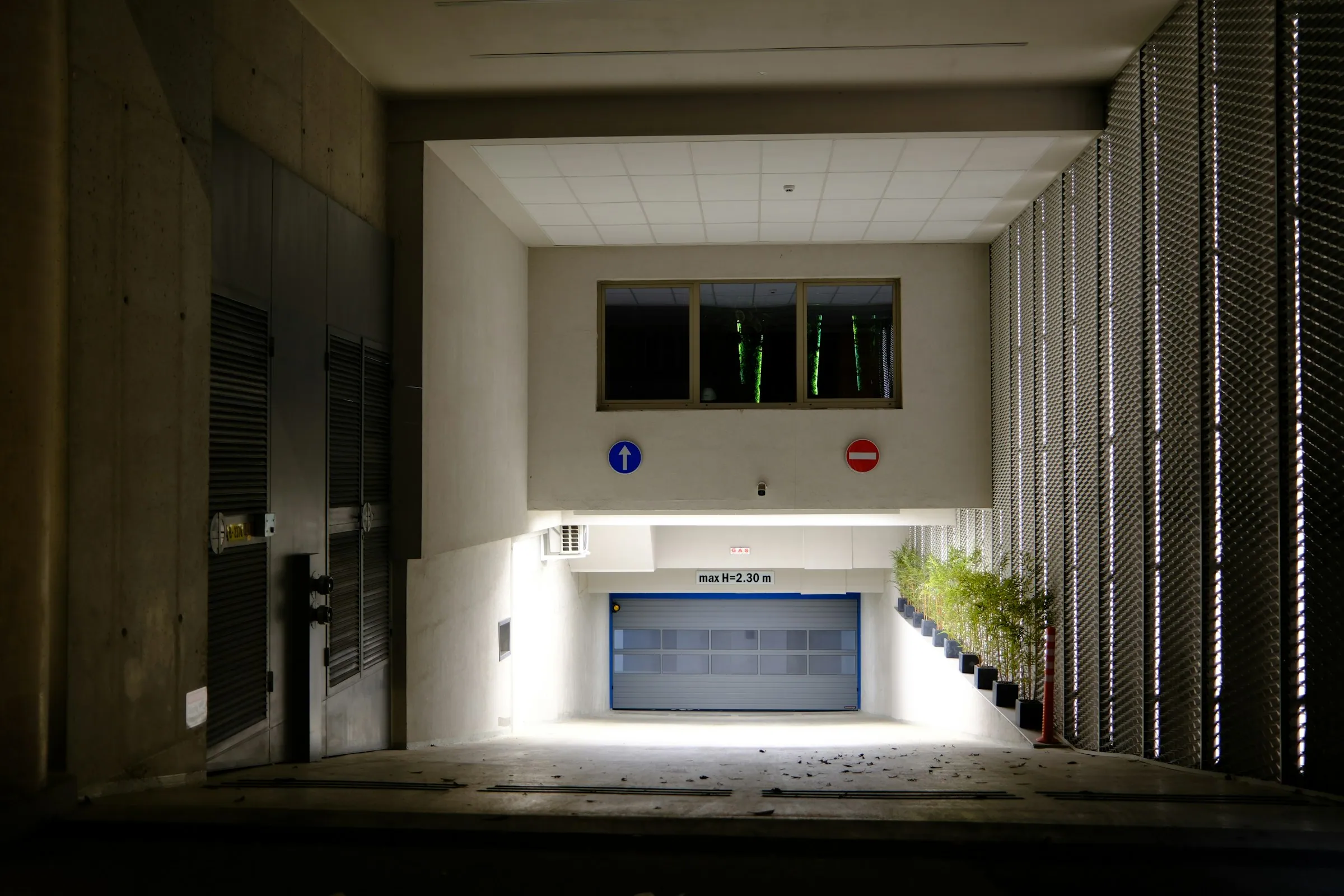 Illuminated modern glass and metal garage entrance at dusk